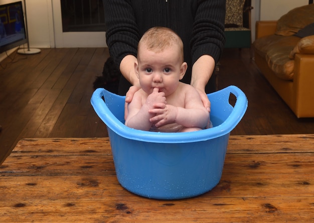 Bébé qui se baigne dans un seau à la maison