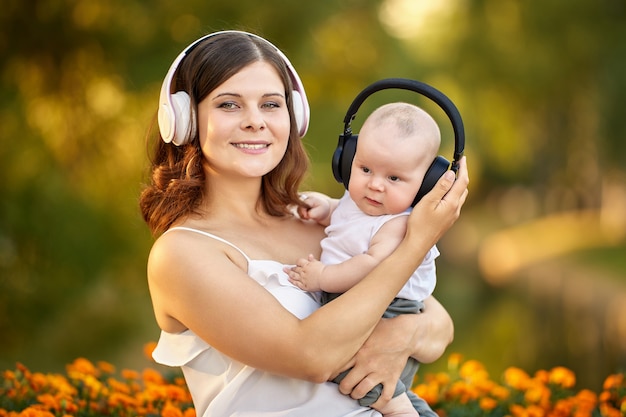 Bébé et sa mère écoutent de la musique avec des écouteurs sans fil dans la nature