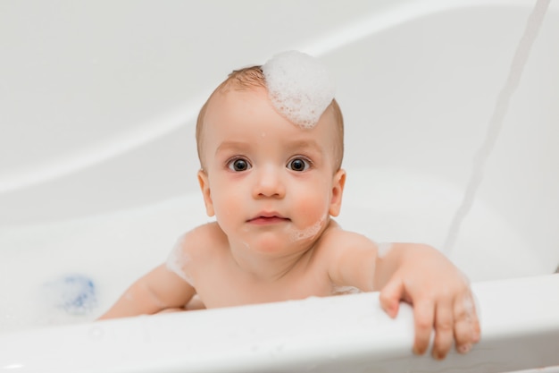 bébé se baigne dans le bain avec de la mousse