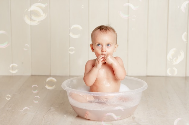 Le bébé se baigne ou se lave dans une bassine avec mousse et bulles de savon