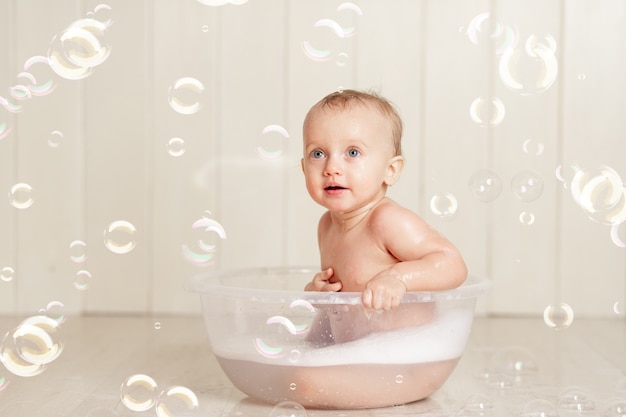 Le bébé se baigne ou se lave dans une bassine avec mousse et bulles de savon