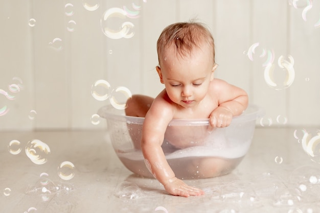 Le bébé se baigne ou se lave dans une bassine avec mousse et bulles de savon