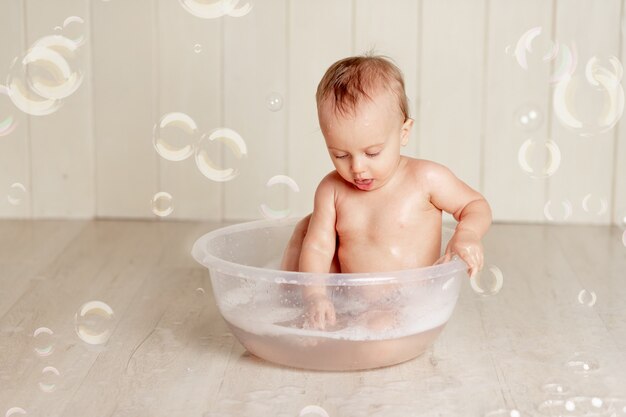 Le bébé se baigne ou se lave dans une bassine avec mousse et bulles de savon