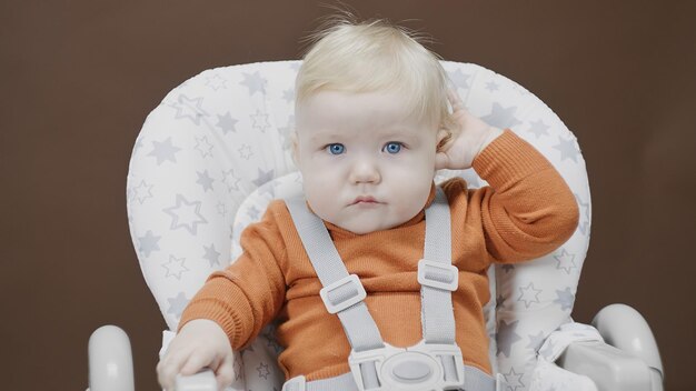 Bébé se gratte l'oreille et regarde la caméra