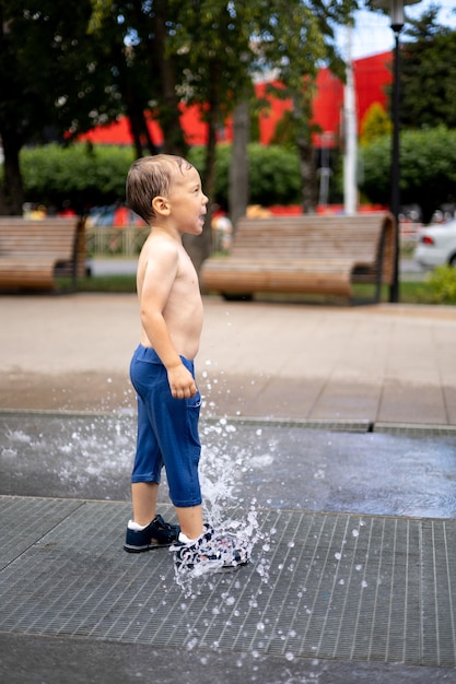 Le bébé se tient dans la fontaine beaucoup d'éclaboussures l'enfant rit une enfance heureuse joyeuse