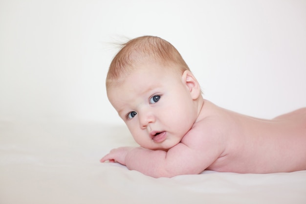 Bébé se trouve sur le ventre sur un fond blanc