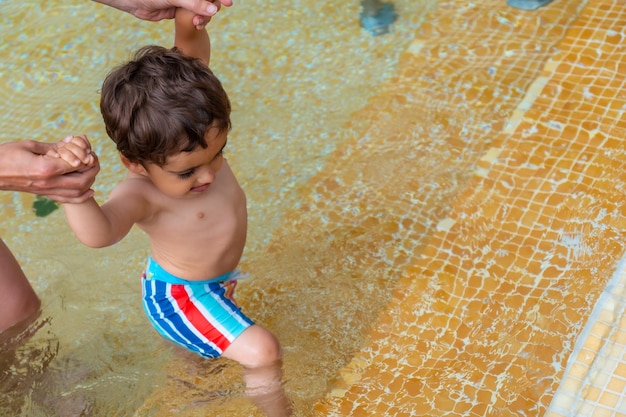 Un bébé sort de la piscine avec l'aide des bras de sa mère