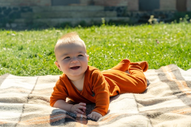 Bébé souriant allongé sur le plaid sur l'herbe ensoleillée Enfant en plein air