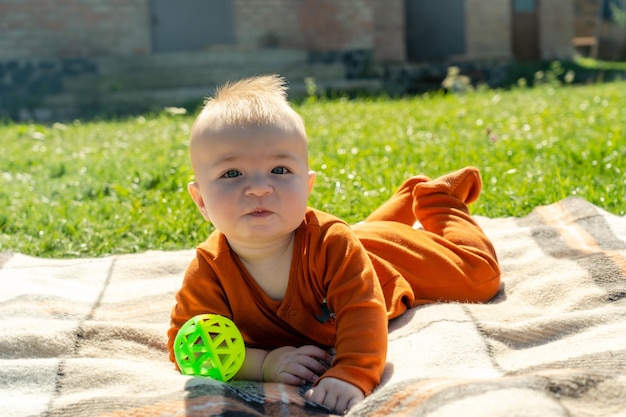 Bébé souriant allongé sur le plaid sur l'herbe ensoleillée Enfant en plein air