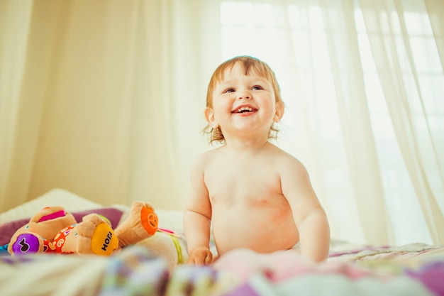 Bébé souriant assis sur un lit