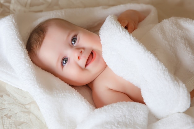 Bébé souriant heureux dans une serviette après le bain