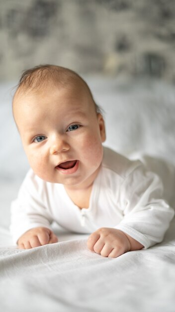 Bébé souriant satisfait allongé sur le ventre sur un fond blanc.