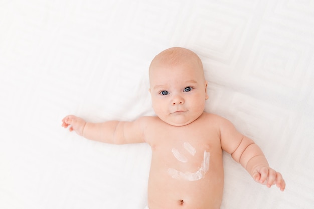 Bébé avec un sourire sur le ventre sur un fond clair