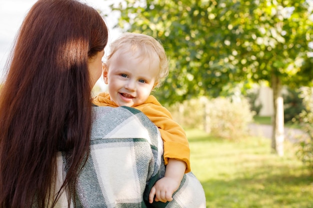 Bébé sourit dans les bras de maman en promenade