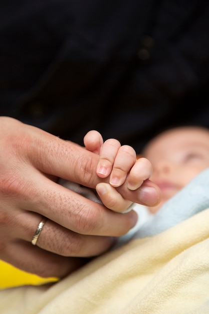 Photo bébé tenant un doigt de parent