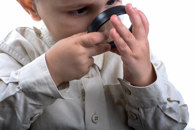 Bébé tenant une loupe à la main sur un fond blanc