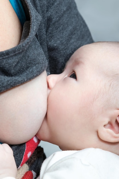 Bébé tète le sein de sa mère et la regarde de près