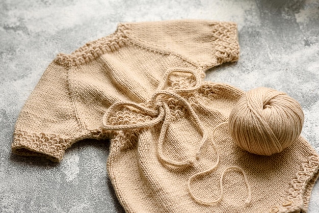 Bébé tricoté des vêtements beiges sur un fond de béton blanc Tricot en passe-temps à la main