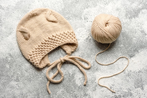 Bébé tricoté des vêtements beiges sur un fond de béton blanc Tricot en passe-temps à la main