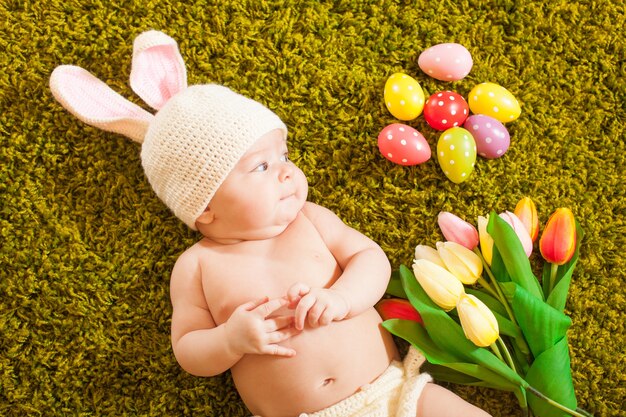 Bébé de trois mois allongé sur le tapis d'herbe comme un lapin de Pâques