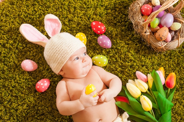 Bébé de trois mois allongé sur le tapis d'herbe comme un lapin de Pâques