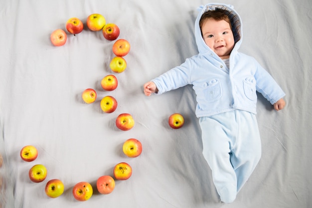 Bébé de trois mois. bébé de trois mois, sur fond gris. a présenté le chiffre trois des pommes.