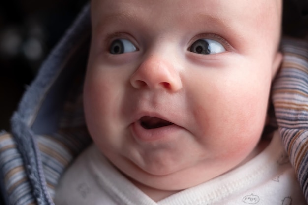 Bébé de trois mois regardant de côté avec une expression surprise finny Qu'entendez-vous par émotion