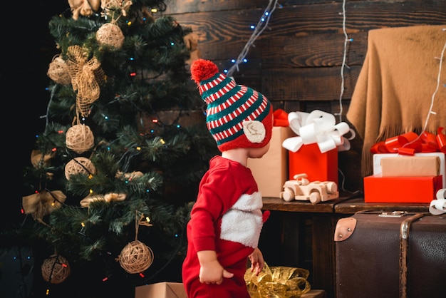 Les bébés heureux petits enfants en bonnet de noel avec cadeau ont un portrait de noël enfant avec cadeau sur bois ...