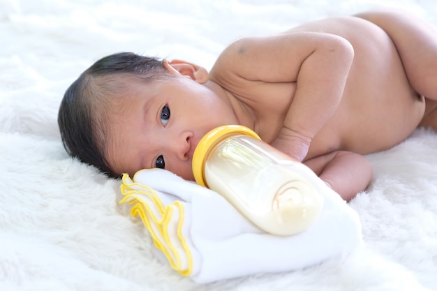 Les bébés sur un lit de bal blanc sont en train de sucer du lait dans un biberon.