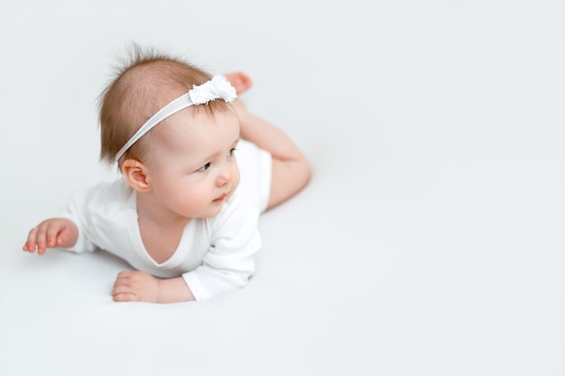 Les bébés sont allongés sur le ventre dans un lit blanc comme neige et regardent attentivement vers l'espace de copie