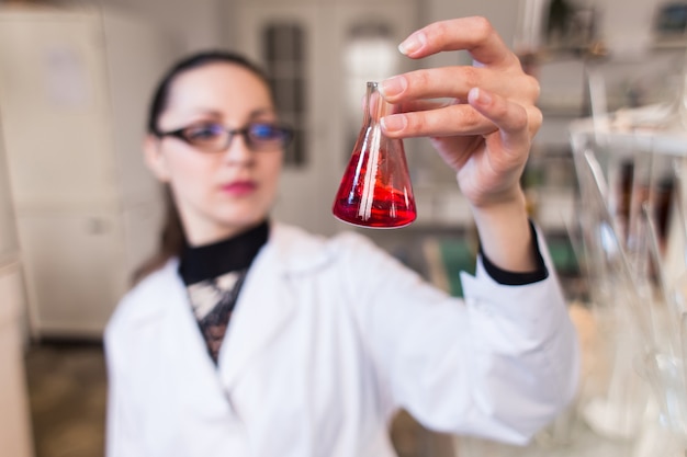Bécher avec du liquide dans les mains des femmes scientifiques