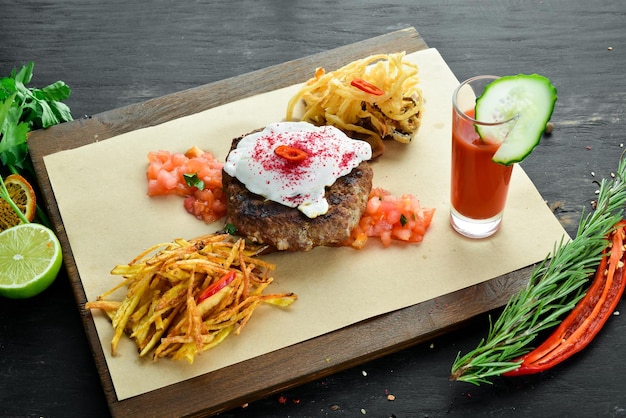 Beefsteak Veau avec œuf poché et jus de tomate Sur un fond en bois Vue de dessus Espace libre pour votre texte