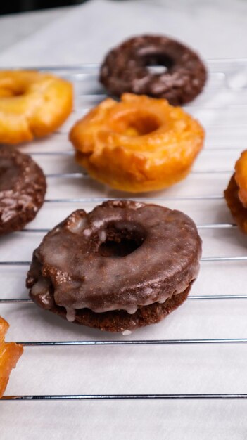 Photo un beignet au chocolat est posé sur une grille à côté d'un beignet au chocolat.