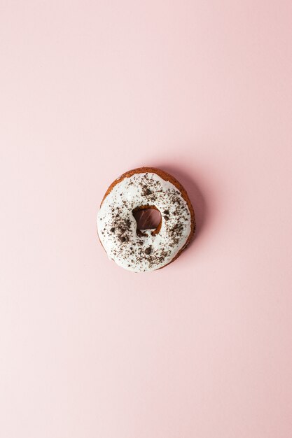 Beignet au chocolat avec glaçage blanc sur fond rose. Vue de dessus. Minimal food et concept de fête