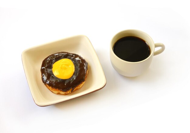 Beignet au chocolat avec une tasse de café isolé sur fond blanc