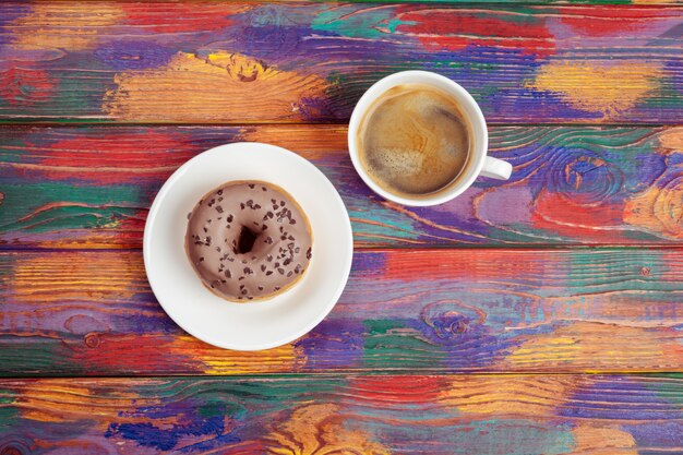 Beignet frais avec du café sur une surface en bois