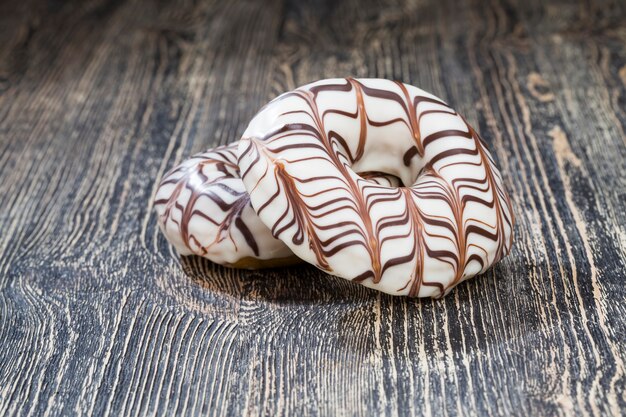 Un beignet frais recouvert de chocolat blanc avec un motif de chocolat au lait