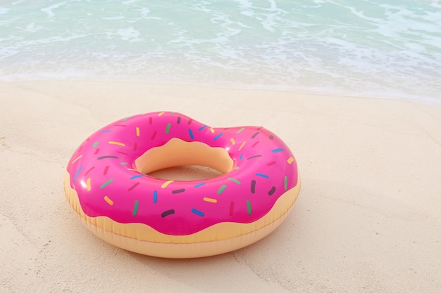 Beignet gonflable coloré sur le sable au bord de la mer