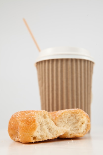 Un beignet à moitié mangé et une tasse de thé placés ensemble