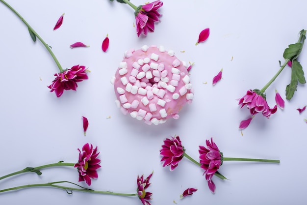 Beignet rose et fleurs sur fond blanc