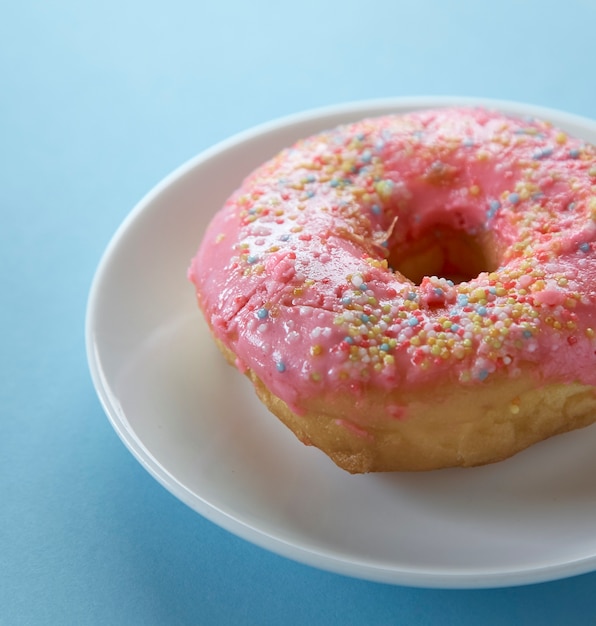 Un beignet rose sur fond bleu