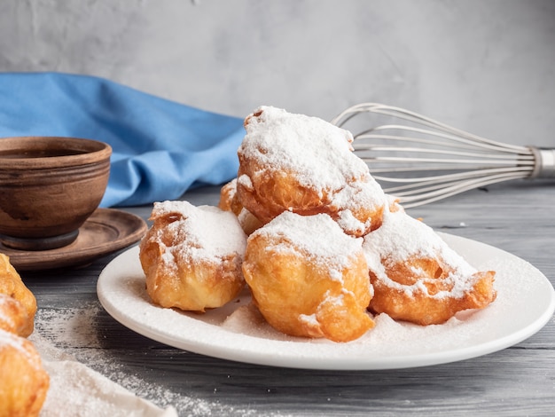 Beignet saupoudré de sucre glace sur une table en bois avec du café et du lait.