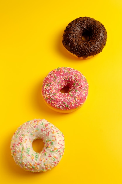 beignets au chocolat rose blanc et noir sur la vue de dessus du mur jaune