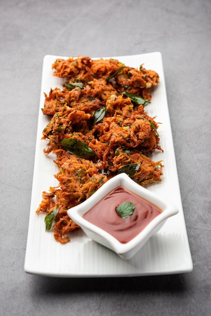 Beignets de carottes ou Gajar ke pakore ou pakode ou bajji ou bhaji, snack indien servi dans une assiette avec du ketchup à la tomate