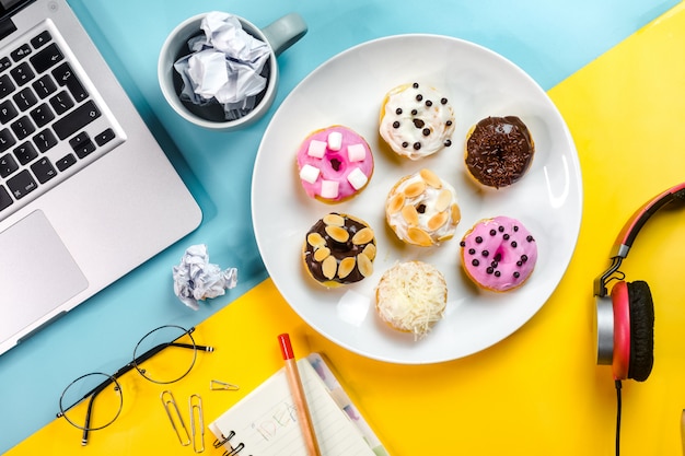 Beignets colorés combinés avec des ordinateurs portables et des objets au bureau