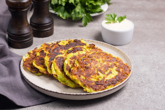 Beignets de courgettes végétariens ou pancakes de courgettes, servis avec des herbes fraîches et de la crème sure.