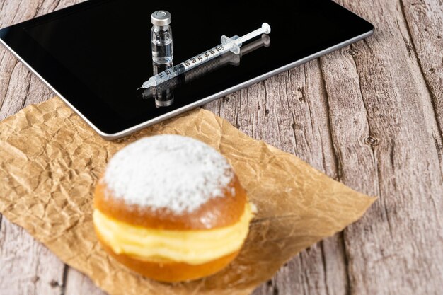 Beignets à la crème brésilienne au premier plan flou En arrière-plan une seringue et une ampoule d'insuline sur la tablette