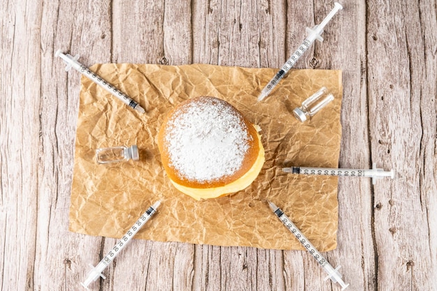 Beignets à la crème brésiliens entourés de diverses seringues et ampoules d'insuline