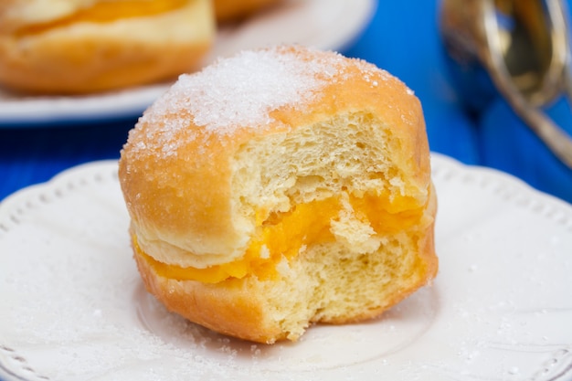 Beignets à la crème d'oeuf dans une boîte en papier blanc sur une surface en bois