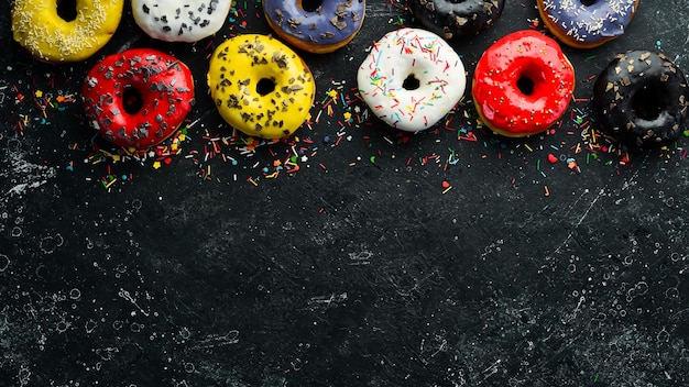 Beignets cuits au four sucrés colorés sur fond noir Vue de dessus Style rustique